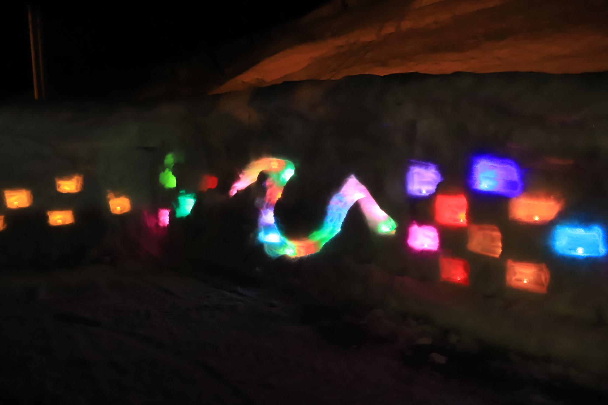 雪壁に何色もの明かりが灯され、ひの文字が浮かび上がっている写真。