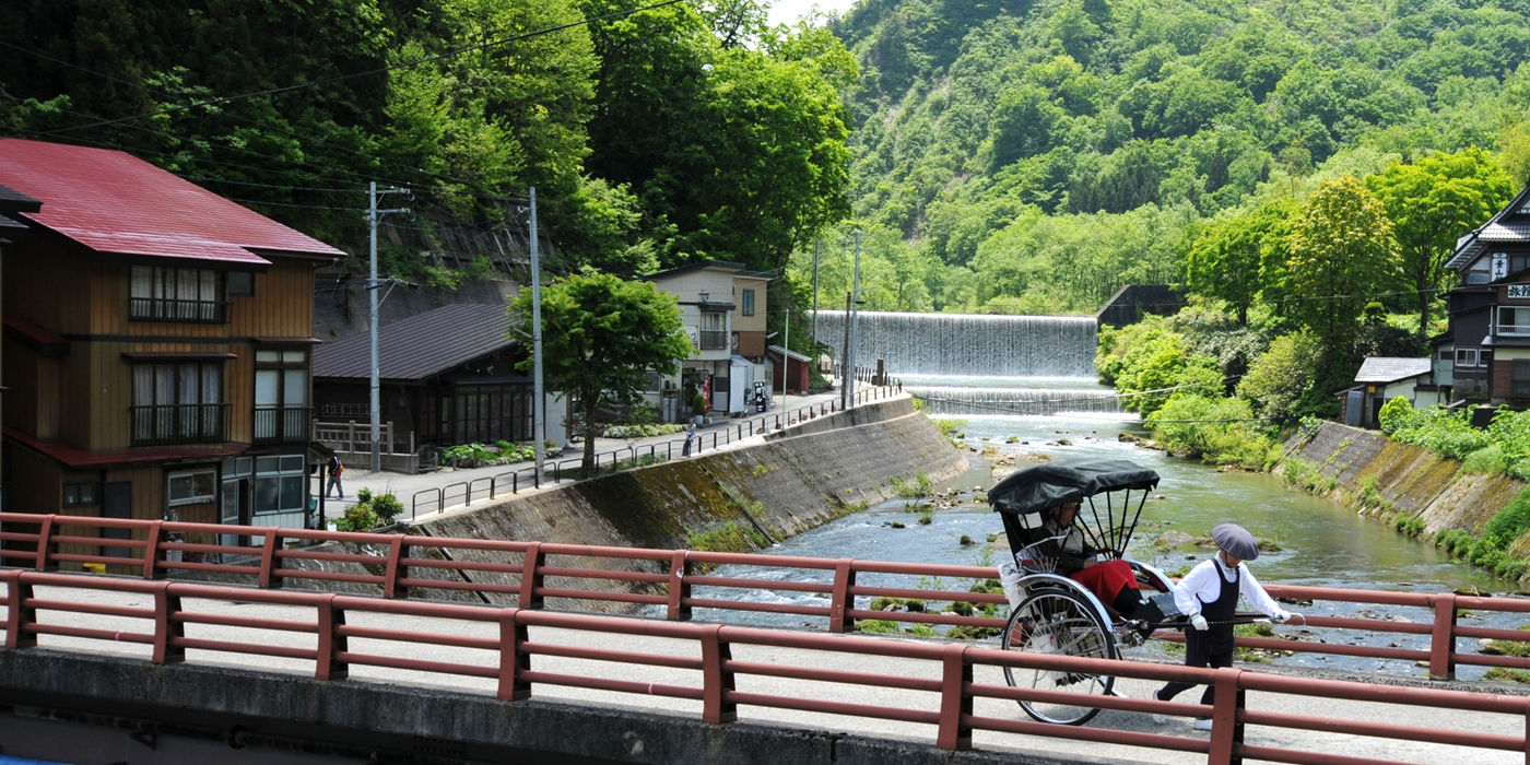 橋の上をお客さんを乗せた人力車が走っていく写真